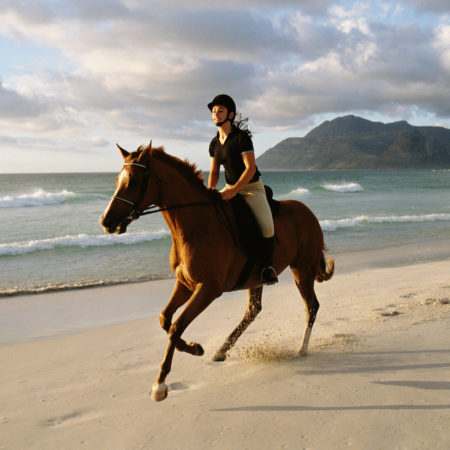 Woman on horseback riding on beach