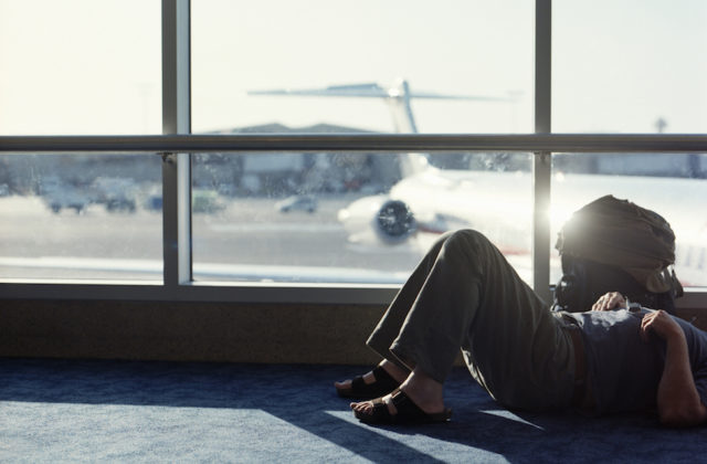 Man lying on floor in airport departure lounge