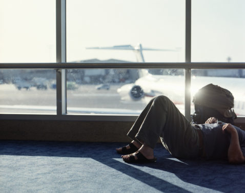 Man lying on floor in airport departure lounge