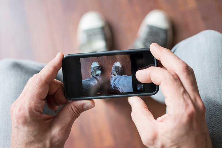 Man photographing his shoes with smartphone