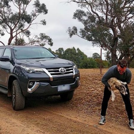 James Banham playing with a dog next to the Toyota Fortuner