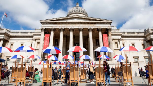 The National Gallery London from the front with umbrellas and tables spread out in Trafalgar Square