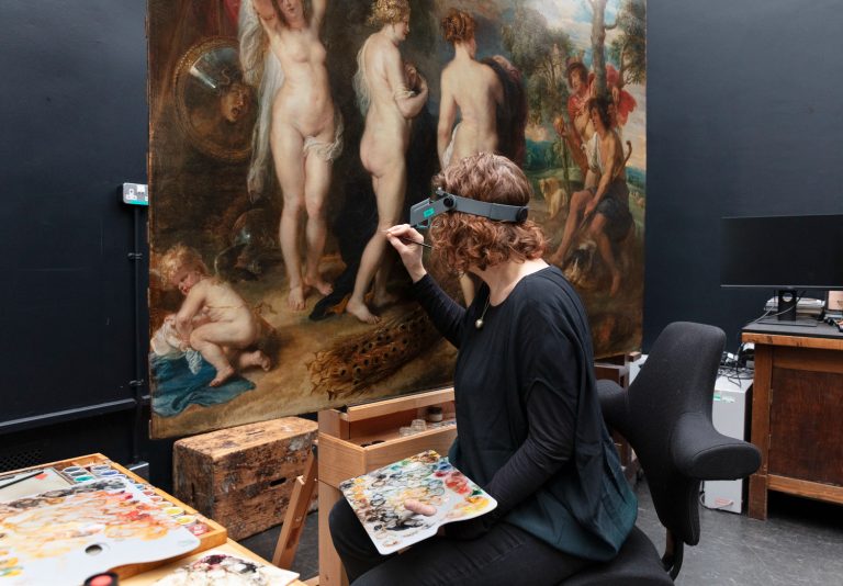 A woman restores an artwork with paint